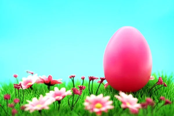 Pink easter egg on meadow with flowers & cyan background Royalty Free Stock Photos