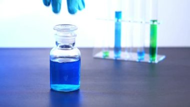 Cam bir şişenin içindeki kimyasal test yeşil hazırlık bir cam kaba dökülüyor..