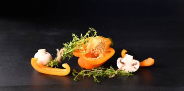 Koyu arkaplanda kekik filizi olan mantar şampiyonları ve kırmızı biber..