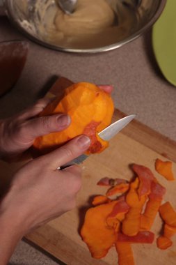 Female hands cut an orange pumpkin with a knife. Skinning a pumpkin with a knife.