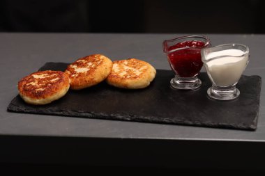Curd pancakes, jam and sour cream on a table in a cafe