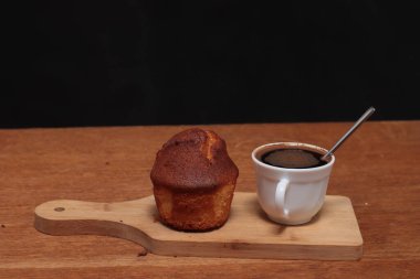 Masanın üzerinde kahve ve çörek var. Kahvaltı için bir fincan kahve ve kek..