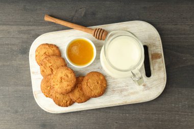 Gri ahşap masada süt, bal ve balkabağı kurabiyeleri.