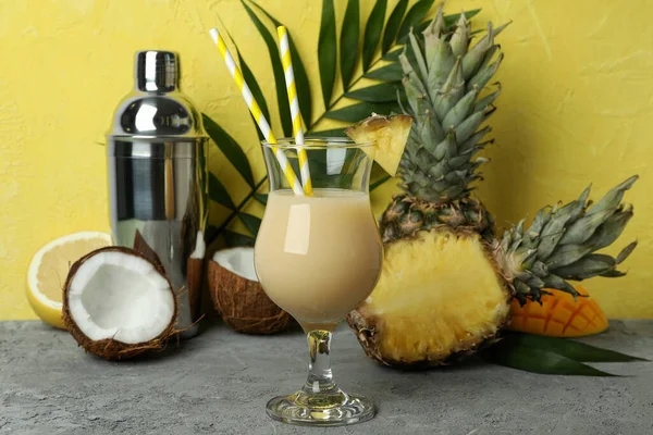 Pina colada kokteyli ve sarı dokulu arka plana karşı malzemeler..