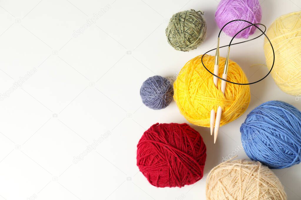 Balls of yarn with knitting needles on white background