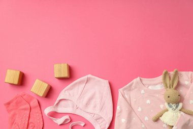 Pembe arka planda kadın bebek kıyafetleri kavramı.