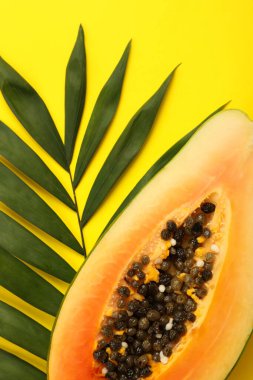 Sarı arka planda Papaya ve palmiye yaprağı.