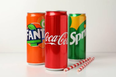 Odessa, Ukrayna - 23 Eylül 2021: Coca - Cola, Sprite ve Fanta kutuları, ve beyaz masa üzerinde pipetler.