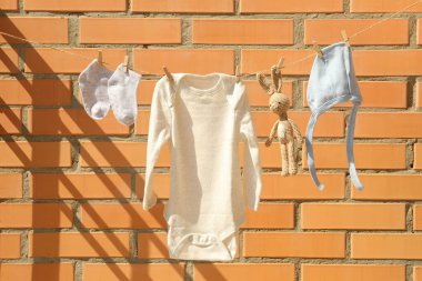 Tuğla duvara karşı çamaşır ipinde çocuk kıyafetleri.