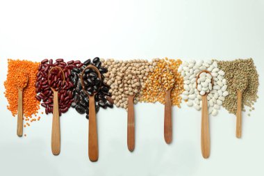 Beyaz arka planda farklı fasulye türlerine sahip kaşıklar.