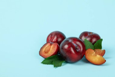 Mavi arkaplanda yaprakları olan erikler.