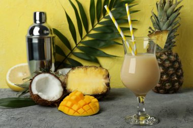 Pina colada kokteyli ve sarı dokulu arka plana karşı malzemeler..