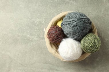 Hasır sepetin içinde açık gri bir arka planda çok renkli iplik topları.
