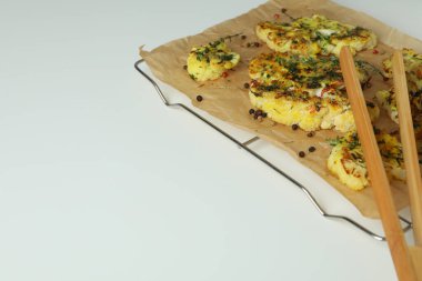 Fırında karnabahar ve beyaz arka planda ahşap maşayla pişirme rafı..