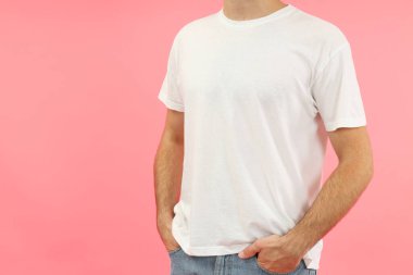 Pembe arka planda beyaz tişörtlü genç adam..