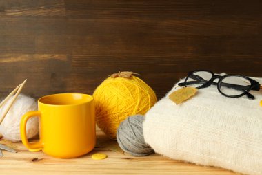 Ahşap masada iplik toplarıyla örgü örme kavramı.