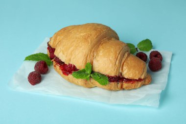 Mavi arka planda ahududu reçeli kruvasan.