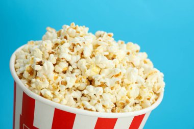 Mavi zemin üzerinde patlamış mısır olan kağıt bardak..