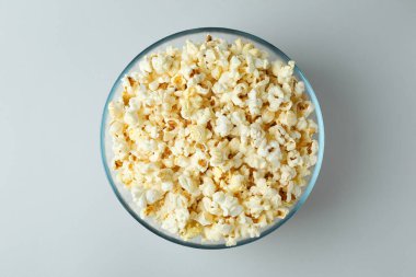 Açık gri arka planda patlamış mısırlı cam kase.