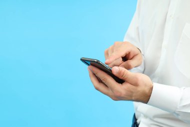 Mavi arkaplanda telefon kullanan işadamı, metin için boşluk.