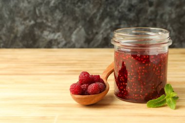 Bir kavanoz ahududu reçeli ve ahşap masa malzemeleri.