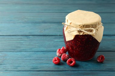 Ahşap zemin üzerine ahududu reçeli kavanozu.