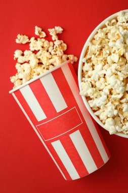 Kırmızı zemin üzerinde patlamış mısır olan kağıt bardaklar.