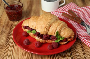 Ahşap arka planda ahududu reçelli kruvasanla lezzetli yemek kavramı