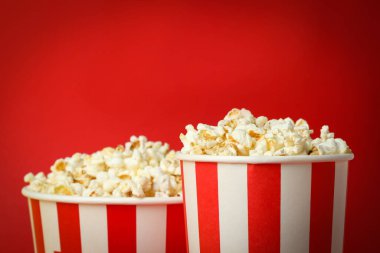 Kırmızı zemin üzerinde patlamış mısır olan kağıt bardaklar.