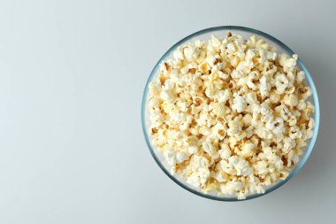 Açık gri arka planda patlamış mısırlı cam kase.