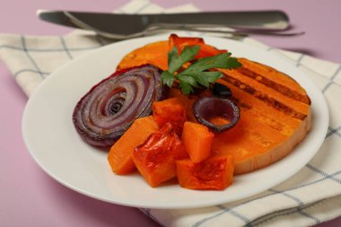 Lezzetli yemek kavramı ve menekşe arkaplanda fırında balkabağı..