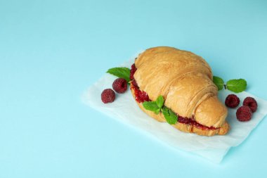 Mavi arka planda ahududu reçeli kruvasan.