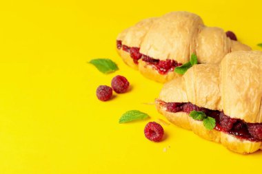 Sarı arka planda ahududu reçelli kruvasan.