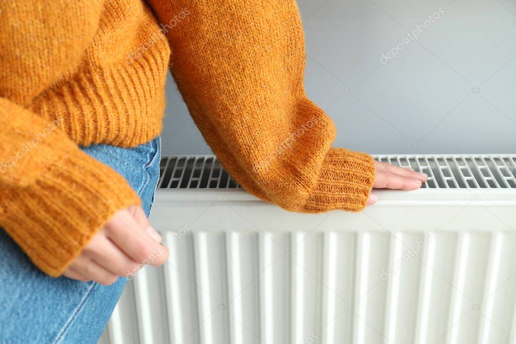 Concept of heating season with girl sitting on radiator.