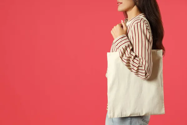Attractive girl holds cotton bag on pink background, space for text.