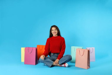 Mavi arka planda renkli kese kağıtları olan kız..