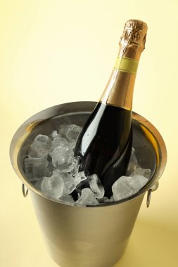 Buzlu metal kova ve bej arka planda şampanya şişesi..