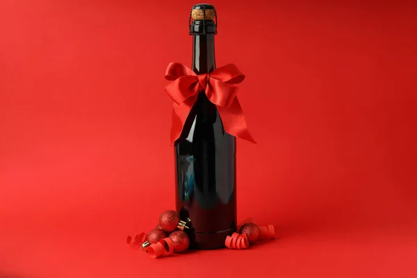 Champagnerflasche Mit Schleife Und Kugeln Auf Rotem Hintergrund — Stockfoto