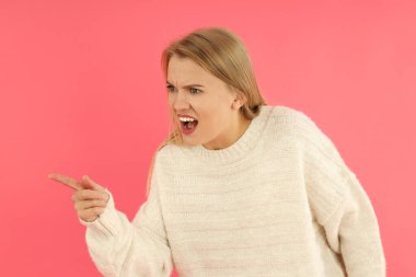 Pembe arka planda hırkalı kızgın bir kız..