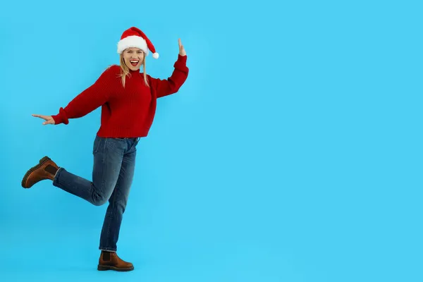 Süveterli Çekici Bir Kadın Mavi Arka Planda Noel Baba Şapkası — Stok fotoğraf