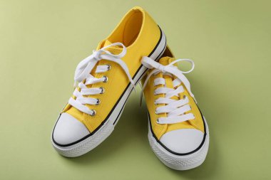 Yeşil arka planda bir çift sarı spor ayakkabı.