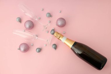 Bir şişe şampanya, pembe arka planda bardaklar ve mücevherler..