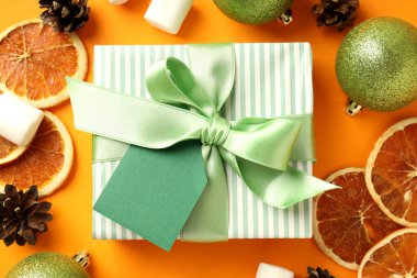 Turuncu arka planda hediye kutusu ve Noel aksesuarları.