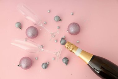 Bir şişe şampanya, pembe arka planda bardaklar ve mücevherler..