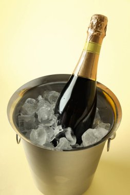 Buzlu metal kova ve bej arka planda şampanya şişesi..
