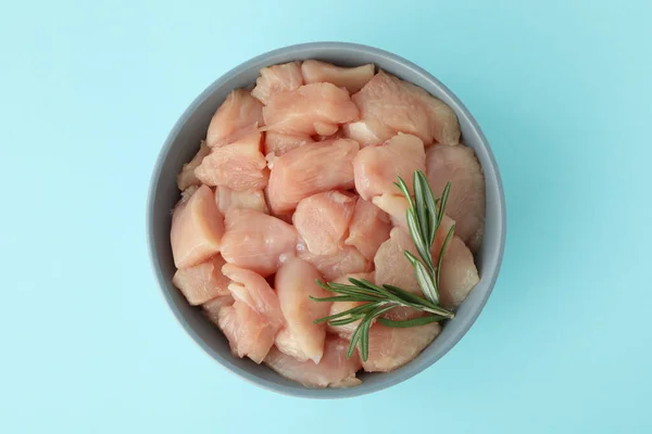 Stock image Pieces of raw chicken fillet in bowl on blue background