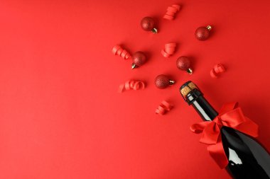 Fiyonklu şampanya şişesi ve kırmızı arka planda takılar..