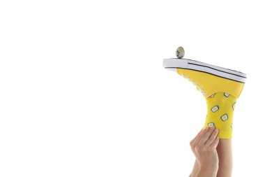 Kadın, beyaz arka planda izole edilmiş bıldırcın yumurtasıyla spor ayakkabısının içine çorap sokuyor.