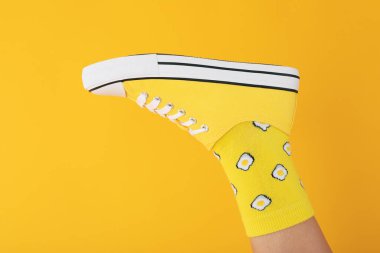 Çorapta kadın bacağı ve sarı arka planda spor ayakkabısı.