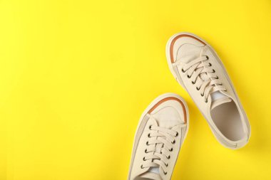 Sarı arka planda bir çift bej spor ayakkabı.